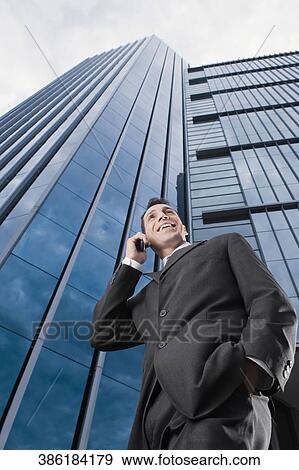 Low angle view of a businessman talking on a mobile phone and smiling View Large Photo Image Stock Photo - Low angle view of a businessman talking on a mobile phone and smiling. Fotosearch