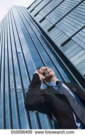 Low angle view of a businessman talking on a mobile phone and laughing View Large Photo Image Stock Photo - Low angle view of a businessman talking on a mobile phone and laughing. Fotosearch