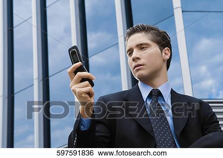 Low angle view of a businessman text messaging View Large Photo Image Stock Photograph - Low angle view of a businessman text messaging. Fotosearch