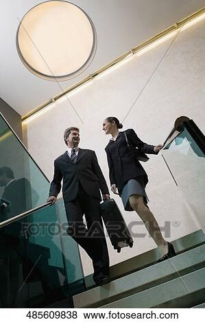 Low angle view of a businessman with a businesswoman moving down staircase View Large Photo Image Stock Photo - Low angle view of a businessman with a businesswoman moving down staircase. Fotosearch