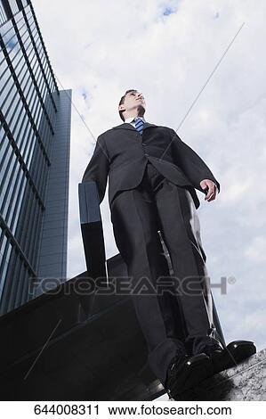 Low angle view of a businesswoman standing on a wall View Large Photo Image Stock Image - Low angle view of a businesswoman standing on a wall. Fotosearch