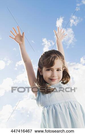 Low angle view of a girl smiling with her arms raised View Large Photo Image Stock Photo - Low angle view of a girl smiling with her arms raised. Fotosearch