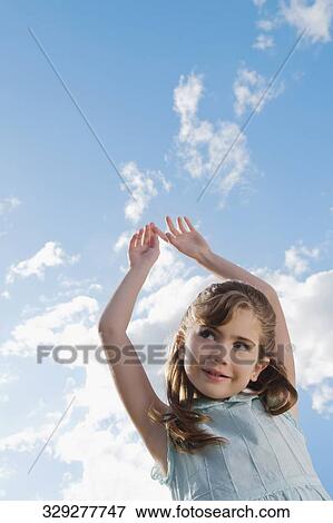 Low angle view of a girl with her arms raised View Large Photo Image Stock Photo - Low angle view of a girl with her arms raised. Fotosearch