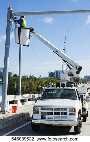 Low angle view of a maintenance engineer on a mobile crane repairing a security camera on a pole View Large Photo Image Stock Image - Low angle view of a maintenance engineer on a mobile crane repairing a security camera on a pole. Fotosearch