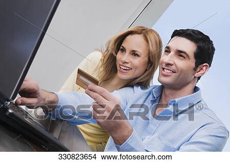 Low angle view of a mid adult couple shopping online View Large Photo Image Picture - Low angle view of a mid adult couple shopping online. Fotosearch