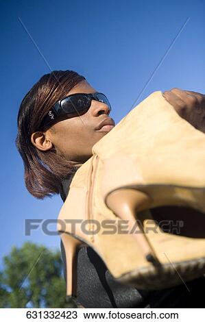 Stock Image - Low angle view of a teenage girl holding high heels. Fotosearch