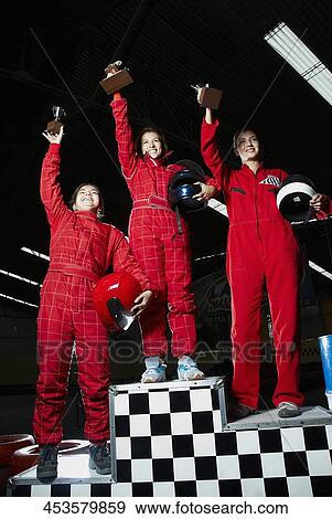 Low angle view of a three female go-carts racers standing on winners podium with their trophies View Large Photo Image Stock Photo - Low angle view of a three female go-carts racers standing on winners podium with their trophies. Fotosearch