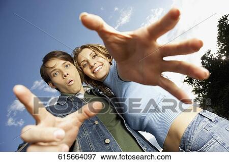 Low angle view of a young couple with their arms outstretched View Large Photo Image Stock Photo - Low angle view of a young couple with their arms outstretched. Fotosearch