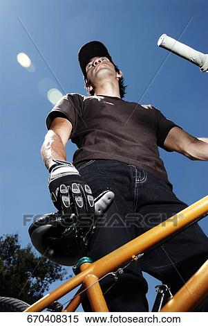 Low angle view of a young man standing with a mountain bike View Large Photo Image Stock Photography - Low angle view of a young man standing with a mountain bike. Fotosearch