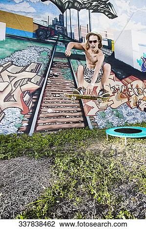 Stock Image - Low angle view of a young man skateboarding. Fotosearch