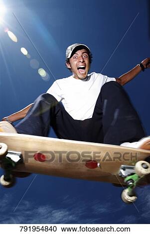 Stock Image - Low angle view of a young man skateboarding. Fotosearch