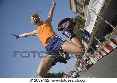 Low angle view of a young woman jumping on the road View Large Photo Image Stock Image - Low angle view of a young woman jumping on the road. Fotosearch