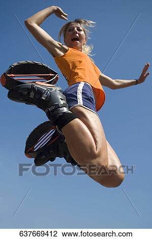 Low angle view of a young woman jumping View Large Photo Image Stock Image - Low angle view of a young woman jumping. Fotosearch