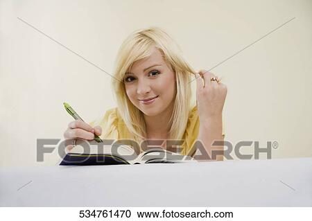 Low angle view of a young woman lying on the bed and writing with a pen in a book View Large Photo Image Stock Image - Low angle view of a young woman lying on the bed and writing with a pen in a book. Fotosearch