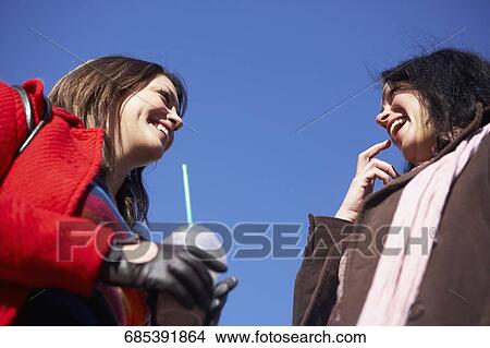 Low angle view of mother and her daughter looking at each other and smiling View Large Photo Image Picture - Low angle view of mother and her daughter looking at each other and smiling. Fotosearch