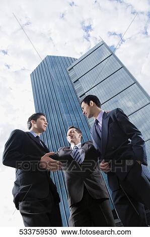 Low angle view of three businessmen discussing in front of skyscrapers View Large Photo Image Stock Image - Low angle view of three businessmen discussing in front of skyscrapers. Fotosearch