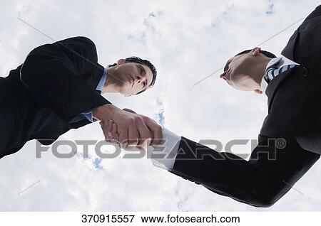 Low angle view of two businessmen shaking hands View Large Photo Image Stock Photo - Low angle view of two businessmen shaking hands. Fotosearch