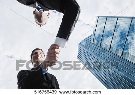Low angle view of two businessmen shaking hands View Large Photo Image Stock Photo - Low angle view of two businessmen shaking hands. Fotosearch