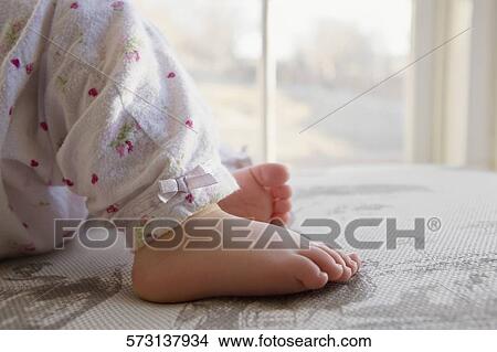 Low section view of a baby girl lying on the bed View Large Photo Image Picture - Low section view of a baby girl lying on the bed. Fotosearch