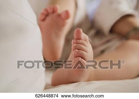 Picture - Low section view of a baby girl sitting on the bed. Fotosearch