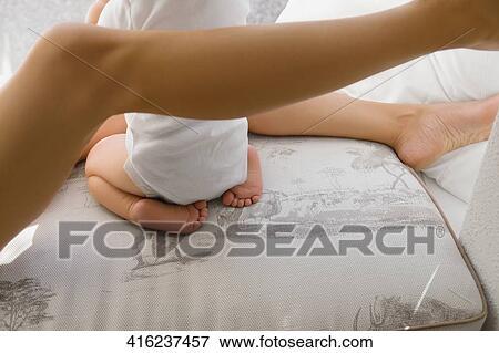 Low section view of a baby girl sitting between her mother's legs View Large Photo Image Stock Photo - Low section view of a baby girl sitting between her mother's legs. Fotosearch