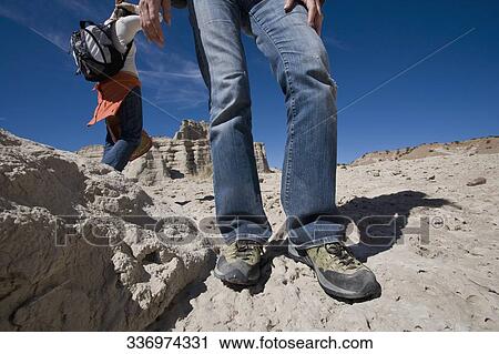 Low section view of a man standing on eroded rocks with a woman walking in the background View Large Photo Image Stock Image - Low section view of a man standing on eroded rocks with a woman walking in the background. Fotosearch
