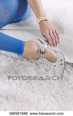 Stock Photo - Low section view of a woman adjusting her high heels. Fotosearch