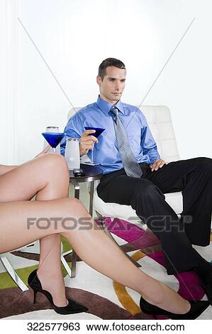 Low section view of a woman with a young man holding a glass of martini beside her View Large Photo Image Stock Image - Low section view of a woman with a young man holding a glass of martini beside her. Fotosearch