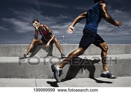 Male athlete running with a female athlete resting on steps and wiping her face View Large Photo Image Stock Photo - Male athlete running with a female athlete resting on steps and wiping her face. Fotosearch