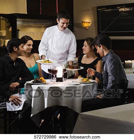 Male chef serving food to two couples in a restaurant View Large Photo Image Stock Photograph - Male chef serving food to two couples in a restaurant. Fotosearch