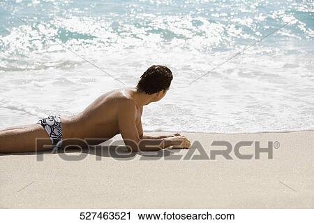 Stock Image - Man sunbathing on the beach. Fotosearch