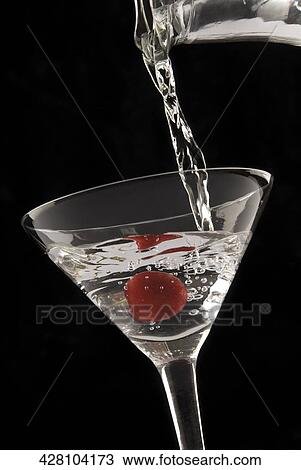 Stock Image - Martini being poured from a bottle into a martini glass. Fotosearch