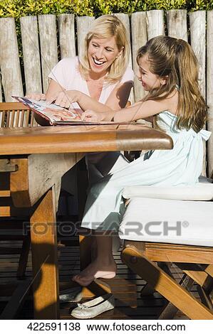 Mature woman reading a book with her granddaughter View Large Photo Image Stock Photo - Mature woman reading a book with her granddaughter. Fotosearch