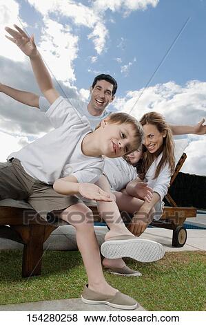 Stock Photo - Mid adult couple playing with their children on a lounge chair. Fotosearch
