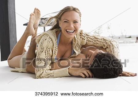 Stock Image - Mid adult couple romancing at the poolside. Fotosearch