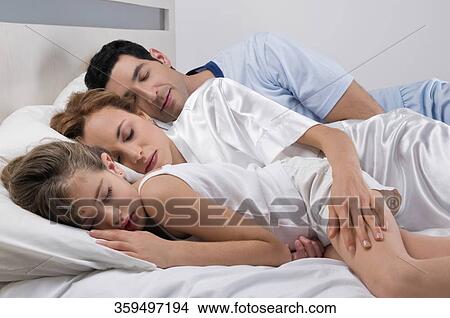 Mid adult couple sleeping with their daughter View Large Photo Image Picture - Mid adult couple sleeping with their daughter. Fotosearch