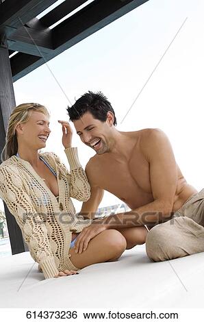 Stock Photograph - Mid adult couple smiling at the poolside. Fotosearch