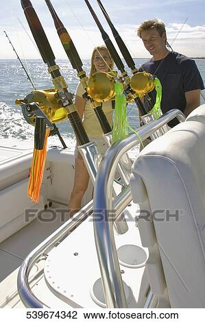 Mid adult couple standing on a speedboat and smiling View Large Photo Image Stock Image - Mid adult couple standing on a speedboat and smiling. Fotosearch
