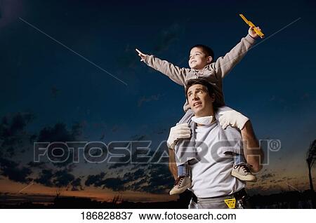 Mid adult man carrying his son on his shoulders View Large Photo Image Stock Photo - Mid adult man carrying his son on his shoulders. Fotosearch