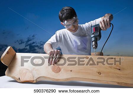 Mid adult man drilling in a wood plank View Large Photo Image Stock Image - Mid adult man drilling in a wood plank. Fotosearch