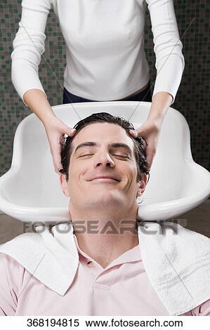 Stock Photography - Mid adult man having a hair wash in the hair salon. Fotosearch