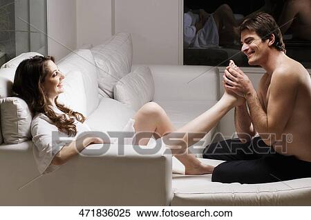 Mid adult man holding the leg of a young woman View Large Photo Image Stock Photography - Mid adult man holding the leg of a young woman. Fotosearch