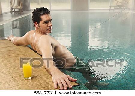 Mid adult man leaning at the poolside View Large Photo Image Stock Image - Mid adult man leaning at the poolside. Fotosearch