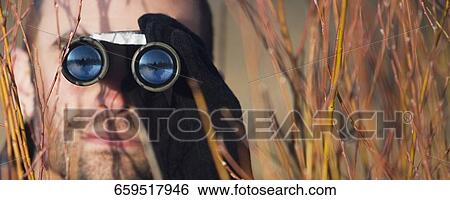 Mid adult man looking through binoculars in a forest View Large Photo Image Stock Photograph - Mid adult man looking through binoculars in a forest. Fotosearch