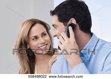 Mid adult man talking on a mobile phone and looking at a mid adult woman View Large Photo Image Stock Image - Mid adult man talking on a mobile phone and looking at a mid adult woman. Fotosearch