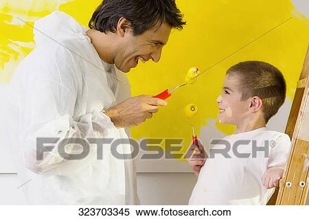 Mid adult man with his son holding paint rollers and looking at each other View Large Photo Image Stock Photography - Mid adult man with his son holding paint rollers and looking at each other. Fotosearch