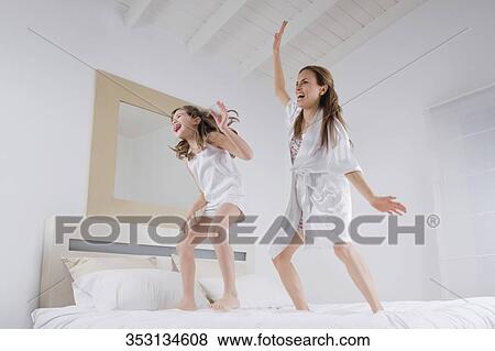 Stock Photo - Mid adult woman dancing on the bed with her daughter. Fotosearch
