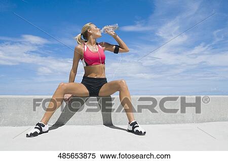 Stock Photography - Mid adult woman drinking water from a water bottle. Fotosearch