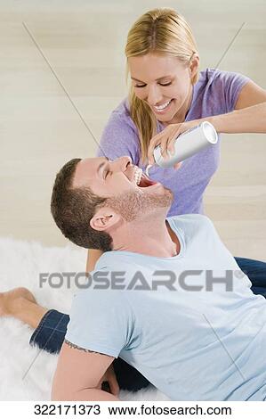 Mid adult woman feeding whipped cream from bottle to a young man View Large Photo Image Stock Image - Mid adult woman feeding whipped cream from bottle to a young man. Fotosearch