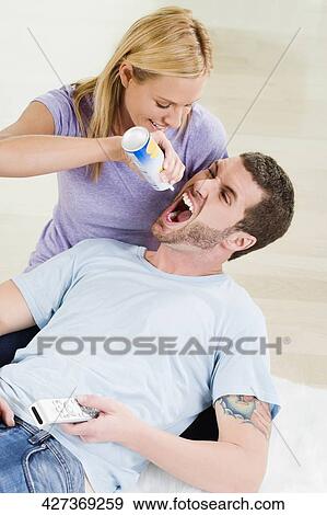 Mid adult woman feeding whipped cream from bottle to a young man View Large Photo Image Stock Photo - Mid adult woman feeding whipped cream from bottle to a young man. Fotosearch